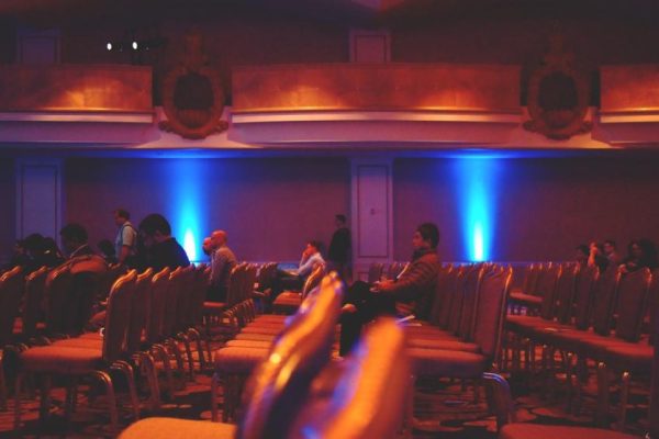 Audience seated in a conference hall lit with blue and red light