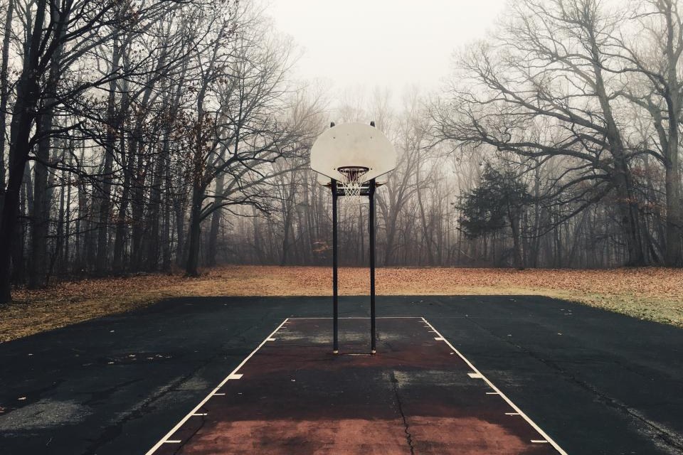 Outdoor basketball court among trees in morning fog