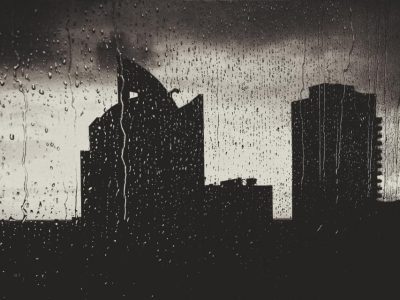 Silhouette of city towers seen through a rain-covered window