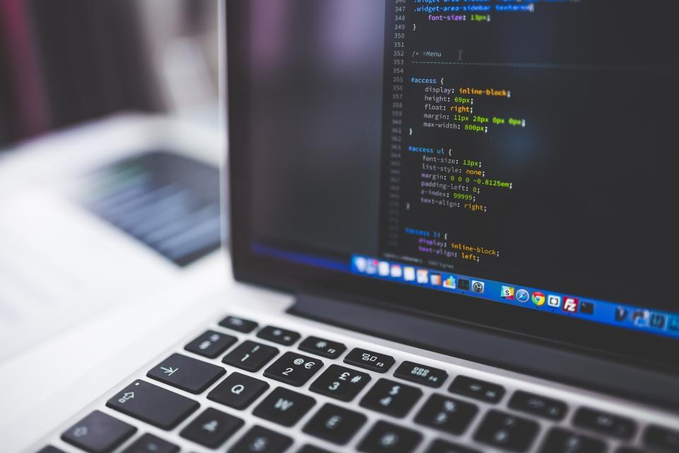 Laptop keyboard and a code editor with colourful syntax
