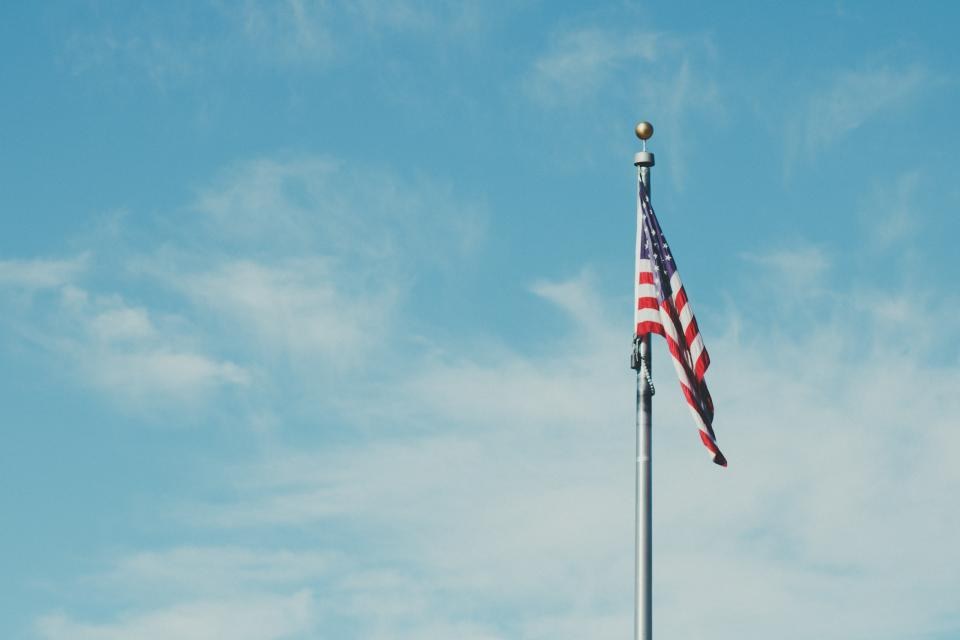 National flag flying on a pole under a blue sky with clouds