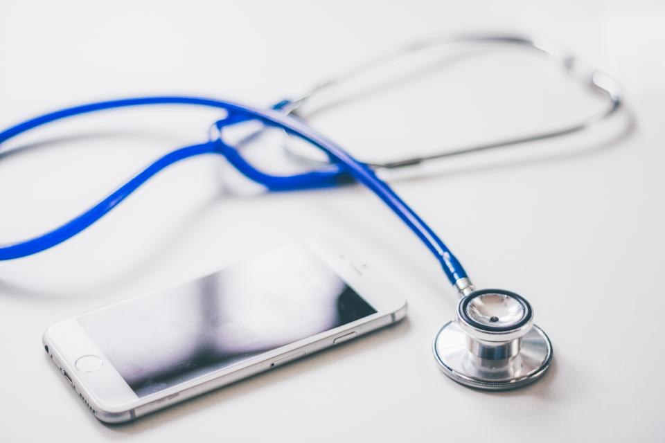 Blue stethoscope resting beside a smartphone