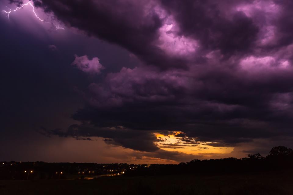 Dark purple storm clouds with lightning at sunset