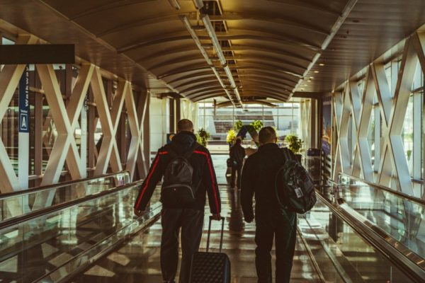 Travellers with luggage walking through an airport walkway
